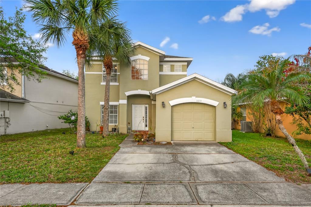 A two-story house with a tan stucco exterior, a single-car garage, and two palm trees — 13230 MEADOWFIELD DR, ORLANDO, FL