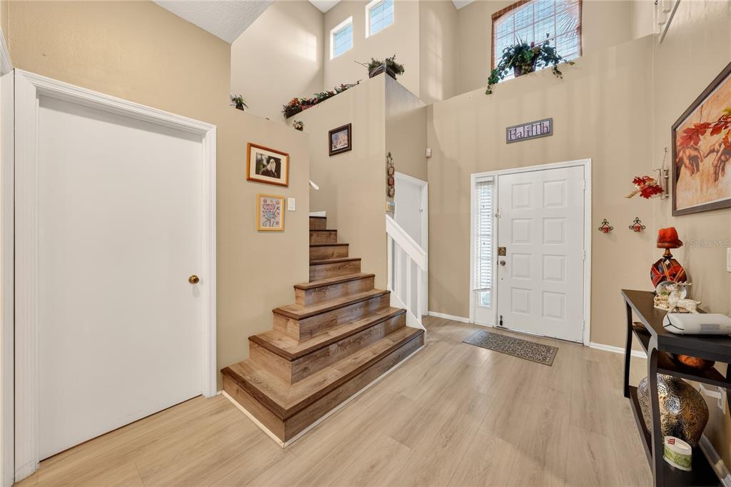 A foyer features light wood-look flooring, a staircase with wood treads, and a white front door — 13230 MEADOWFIELD DR, ORLANDO, FL