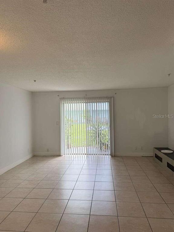 A living room with light-colored tile flooring and a sliding glass door leading outside — 4251 NW 5TH STREET UNIT 121, FORT LAUDERDALE, FL