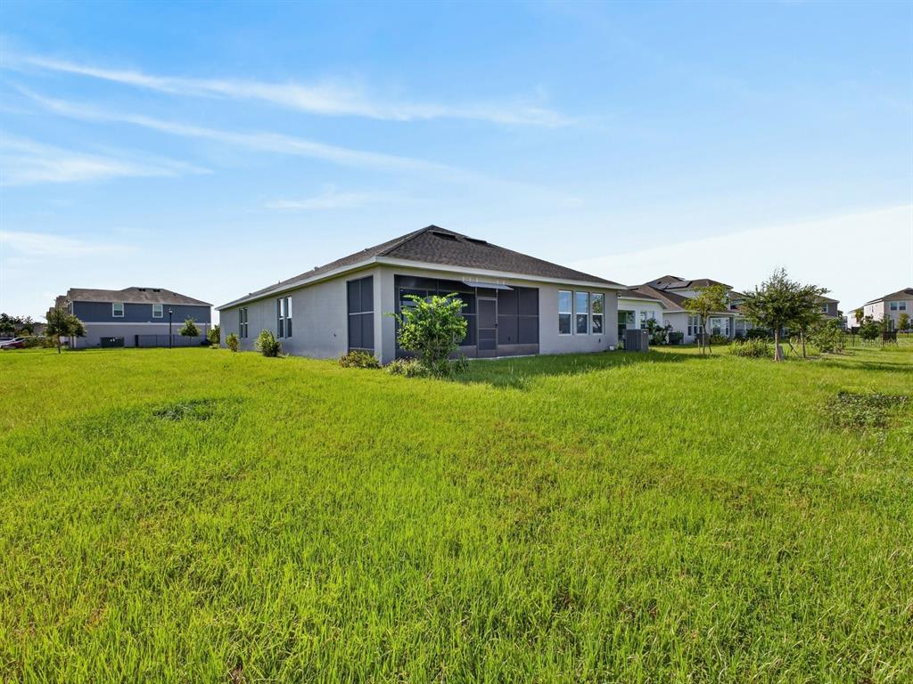 A view of the rear exterior of a single-story house with a screened-in patio — 4666 ACKEE ROAD, KISSIMMEE, FL
