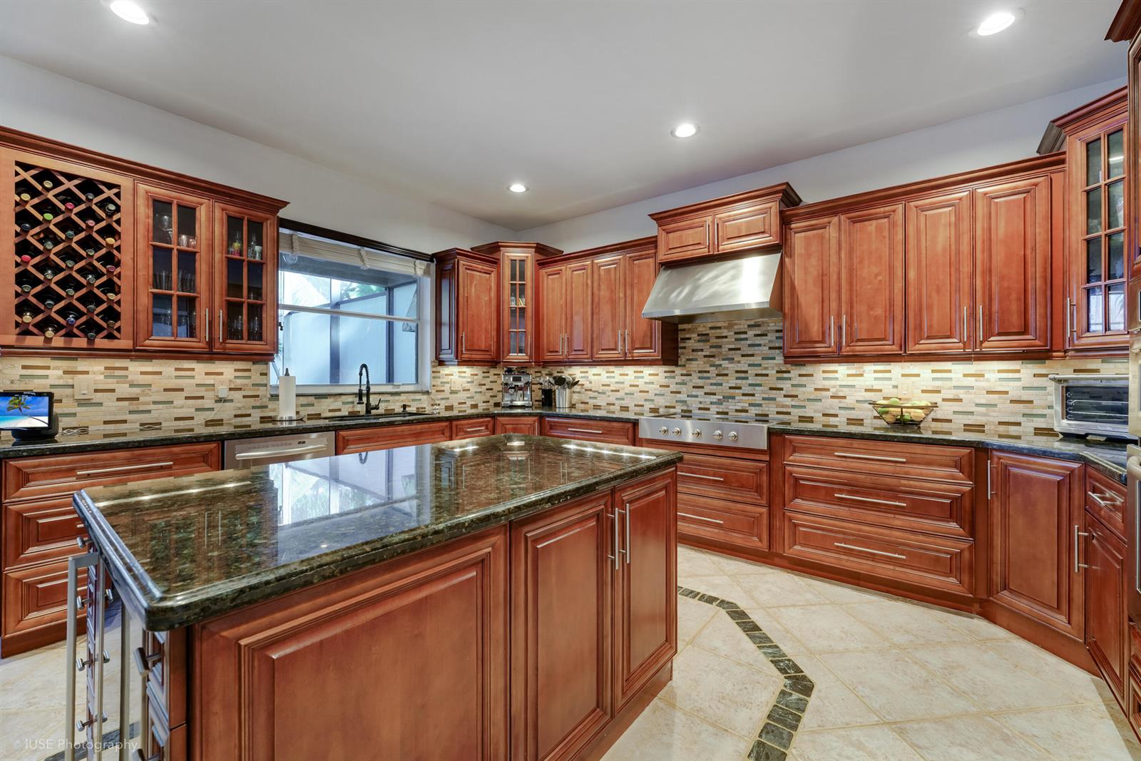A kitchen featuring wood cabinets, a granite-topped island, and a tiled backsplash — 3181 SW 173rd Terrace, Miramar FL 33029, MIRAMAR, FL