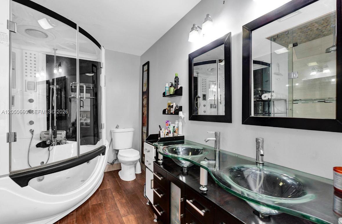 A bathroom features a glass-enclosed shower, a double vanity with glass sinks, and a toilet — BOCA RATON, FL