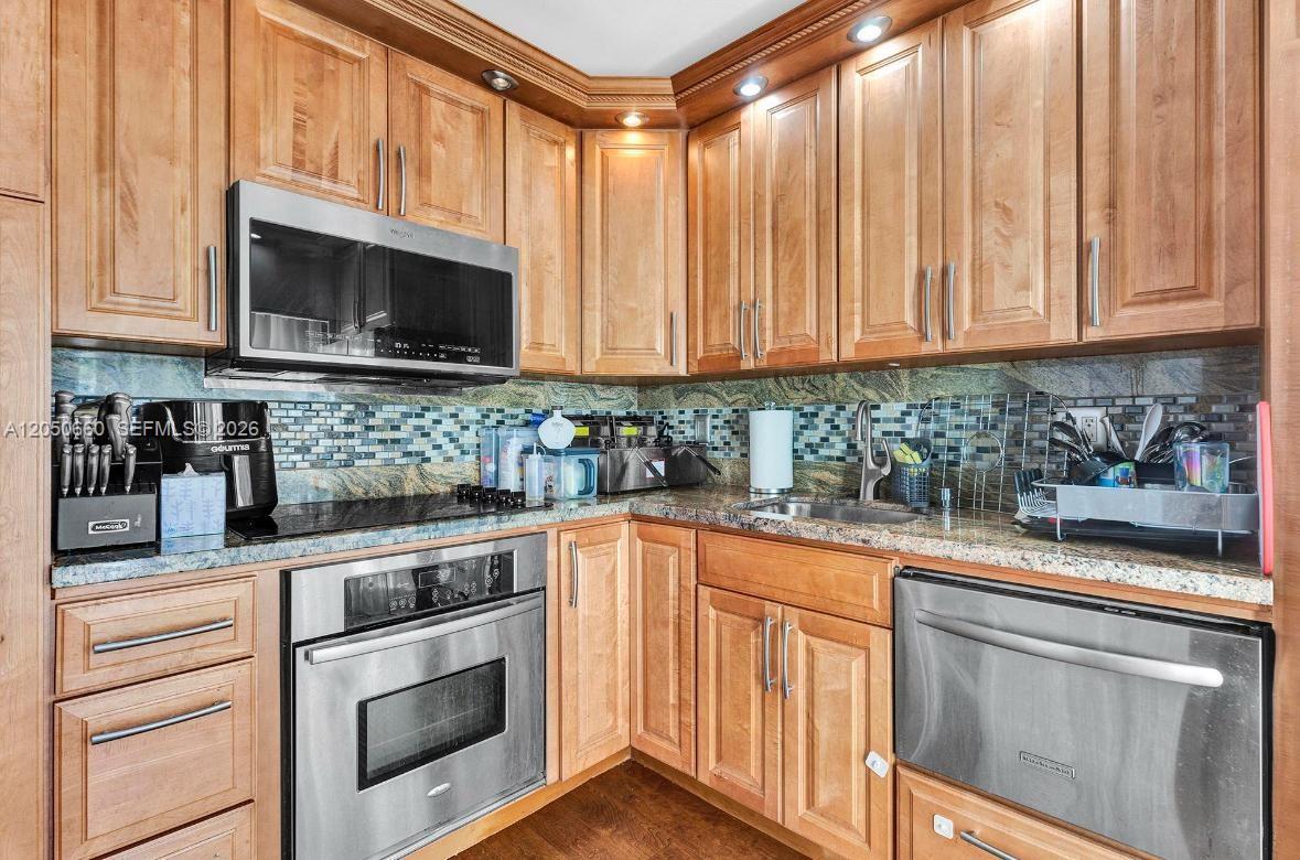 A kitchen features light wood cabinets, stainless steel appliances, and a granite countertop — BOCA RATON, FL