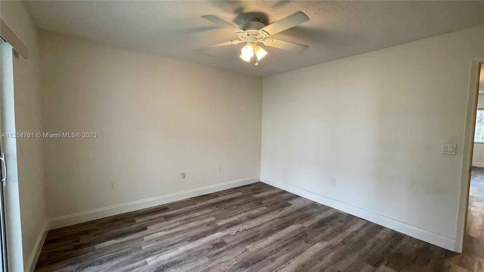 An empty room features white walls, a ceiling fan, and wood-look laminate flooring — 2878 Donnelly Drive # 204, Atlantis FL 33462, ATLANTIS, FL