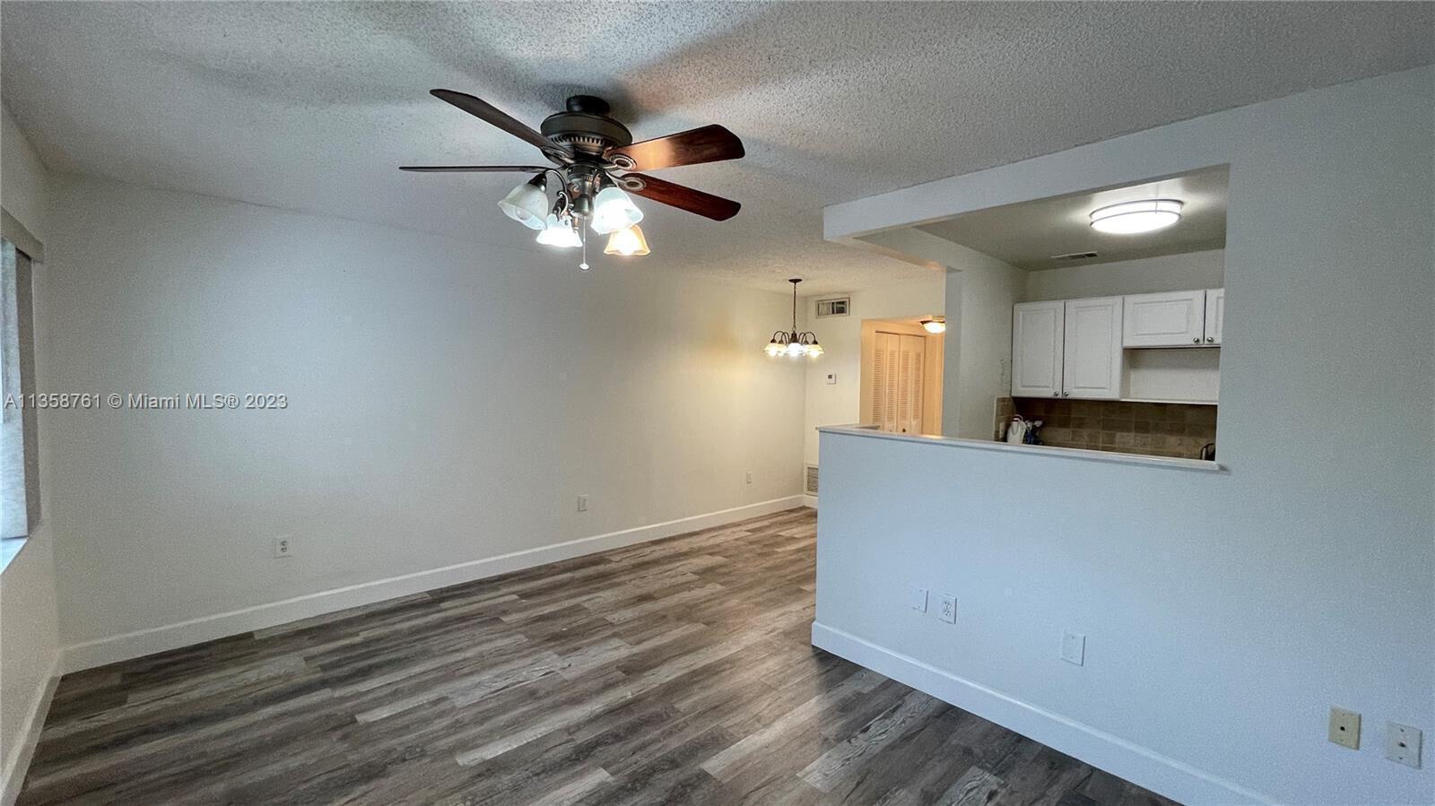 A living room with wood-look flooring, a ceiling fan, and an open kitchen pass-through — 2878 Donnelly Drive # 204, Atlantis FL 33462, ATLANTIS, FL