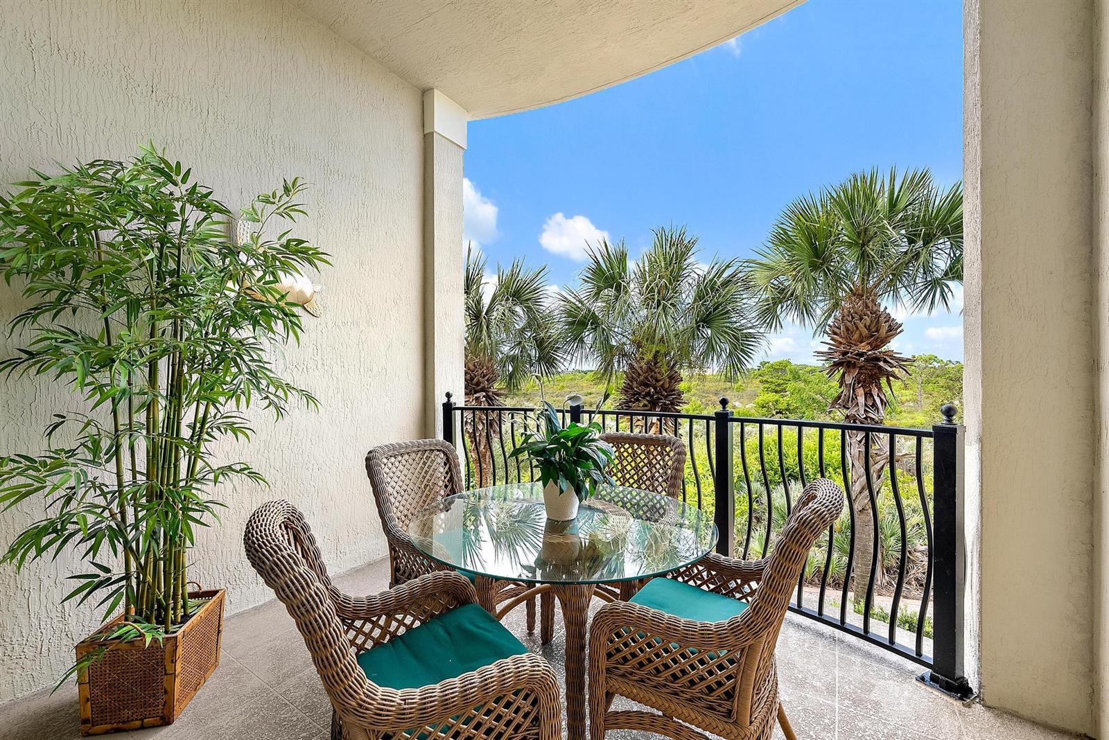 A covered balcony features a glass-topped wicker table, four chairs, and a potted bamboo plant — 138 Tierra Lane # 6, Jupiter FL 33477, JUPITER, FL