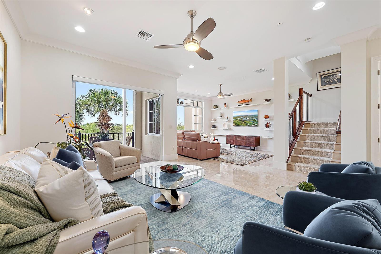 A spacious living room features tile floors, a glass coffee table, and a staircase — 138 Tierra Lane # 6, Jupiter FL 33477, JUPITER, FL