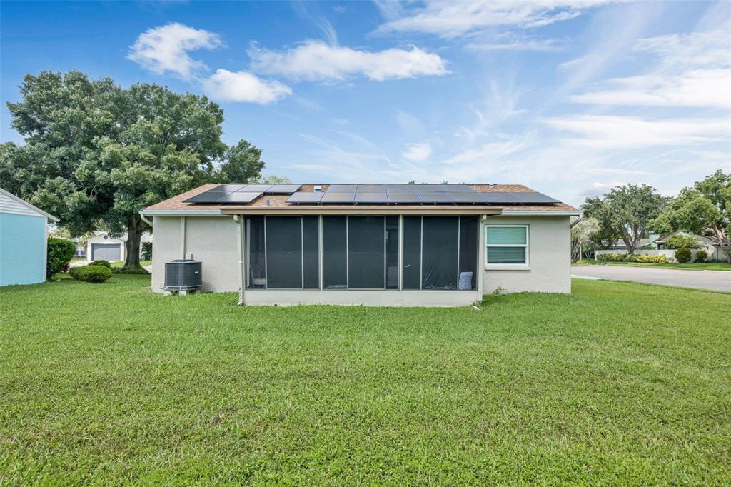 The exterior of a single-story house features a screened-in porch and rooftop solar panels — 3900 105TH AVENUE N, CLEARWATER, FL