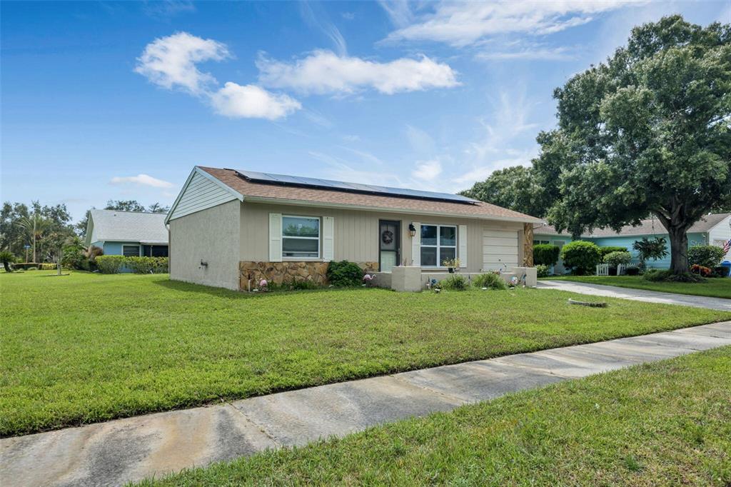 A single-story house with solar panels on the roof and a stone-accented front exterior — 3900 105TH AVENUE N, CLEARWATER, FL