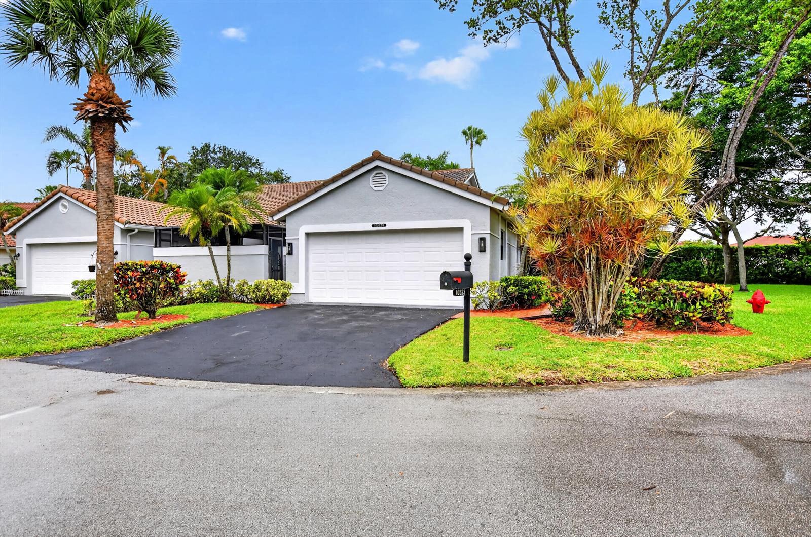 A gray single-story house with a white garage door, palm trees, and a paved driveway — 10523 Ladypalm # B, Boca Raton FL 33498, BOCA RATON, FL