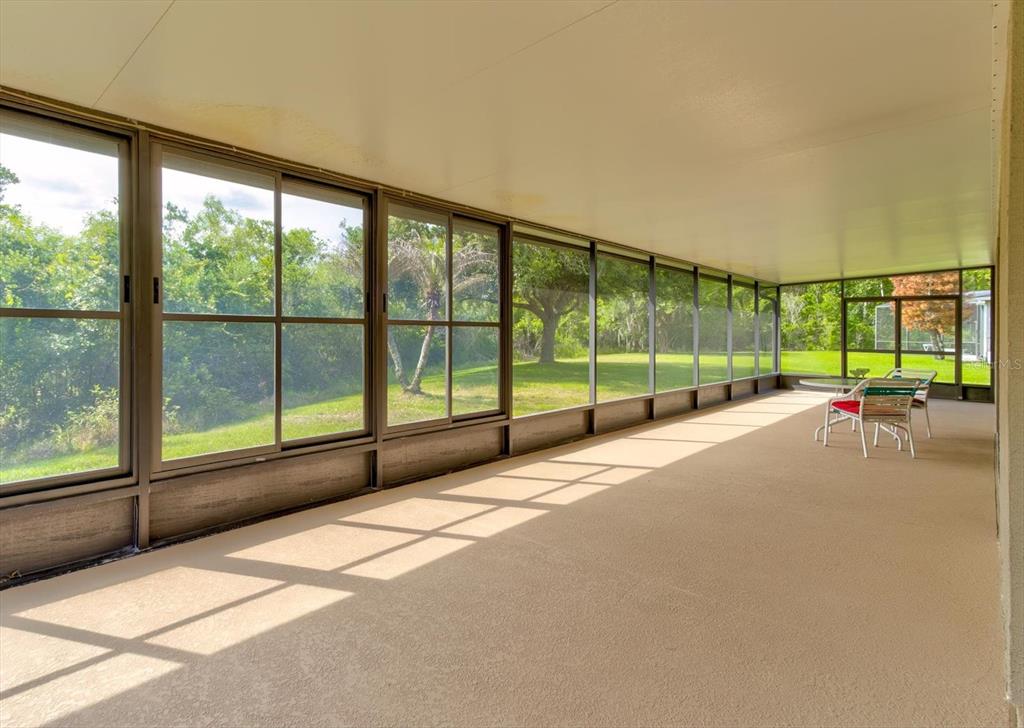 A screened-in porch with a concrete floor, large windows, and a view of trees — 2609 CORBYTON COURT, ORLANDO, FL