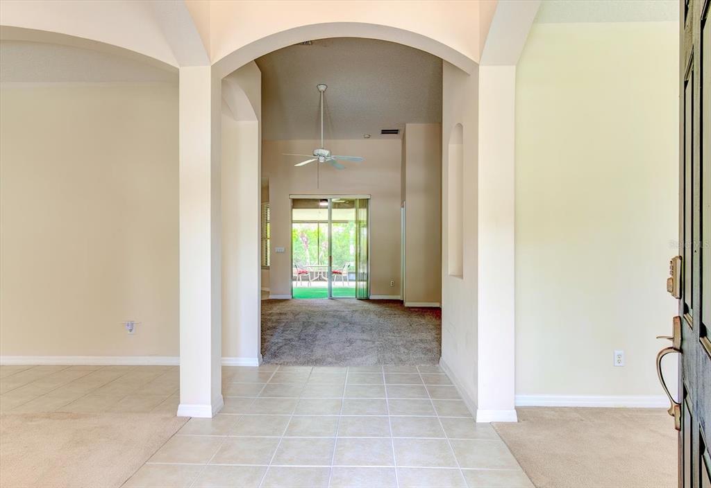 An entryway with tile flooring leads through an arched opening to a carpeted living area — 2609 CORBYTON COURT, ORLANDO, FL