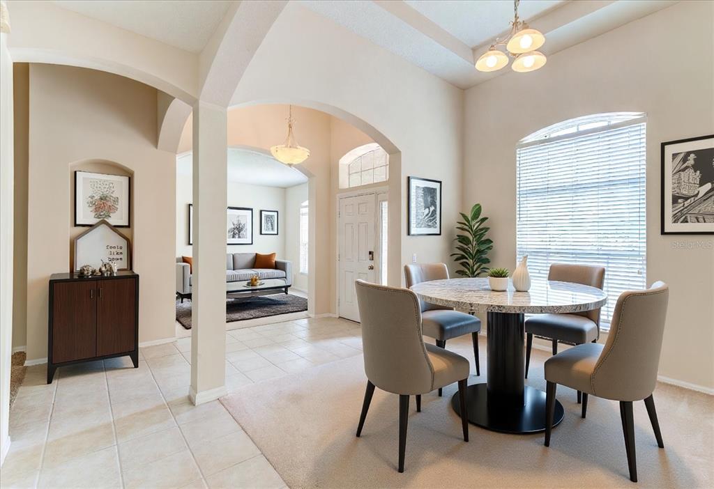 A dining area with a round marble table and chairs sits near an arched entryway — 2609 CORBYTON COURT, ORLANDO, FL