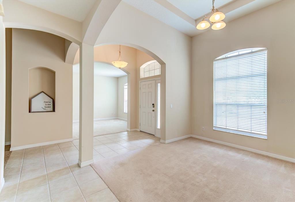 An interior view shows a carpeted living area, tiled entryway, arched doorways, and a front door — 2609 CORBYTON COURT, ORLANDO, FL