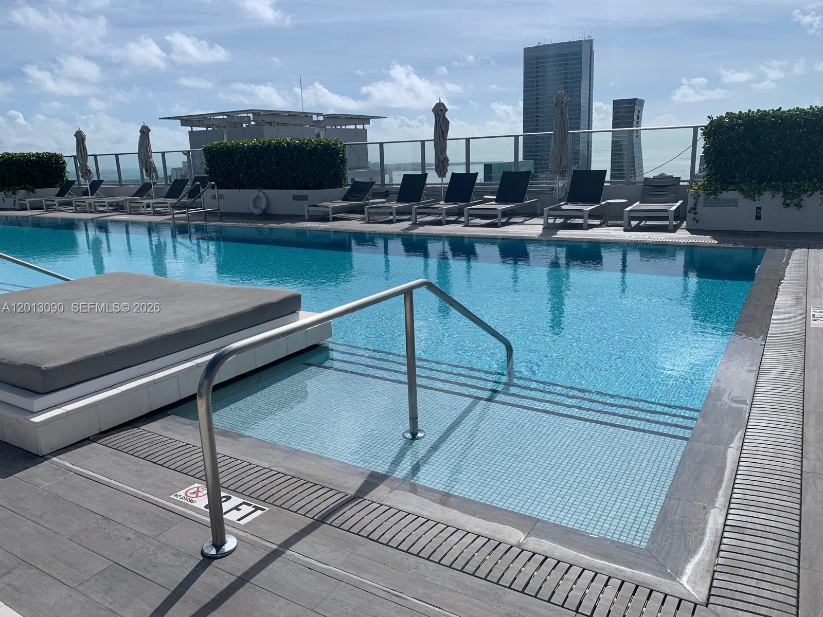 An empty room with white tile floors, a pendant light, and a view of a skyscraper — 1010 Brickell Ave # 3704, Miami FL 33131, MIAMI, FL