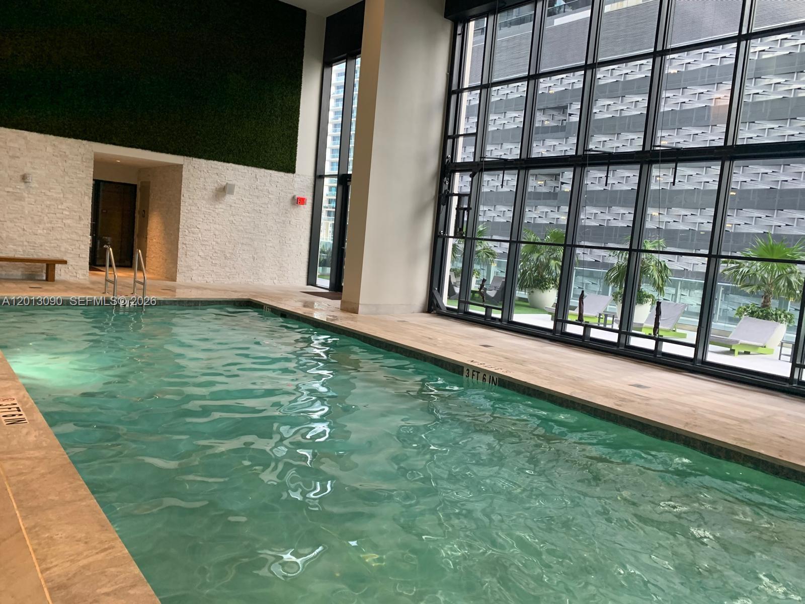 A bright, modern interior features white tile flooring, a bathroom, and a distant balcony view — 1010 Brickell Ave # 3704, Miami FL 33131, MIAMI, FL