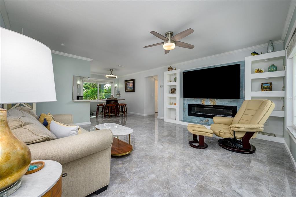 A living room with gray tile floors, a fireplace, a television, and a recliner — 1472 QUEEN ANNE DRIVE, PALM HARBOR, FL