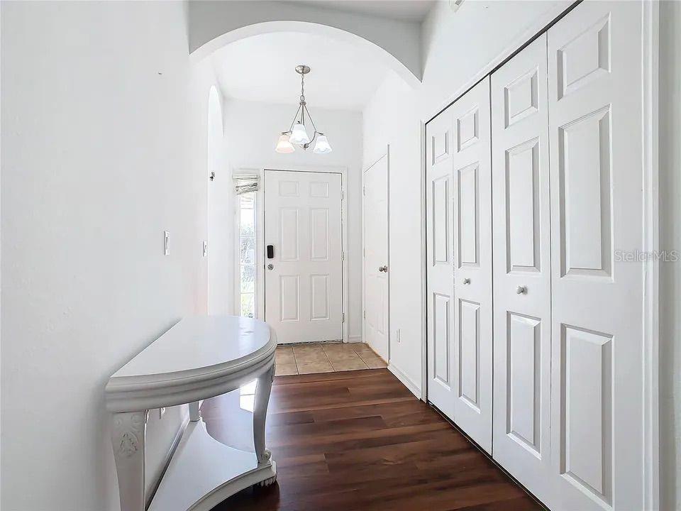 A bright entryway features wood-look flooring, a white console table, and a white front door — 4715 HEMINGWAY HOUSE STREET, KISSIMMEE, FL
