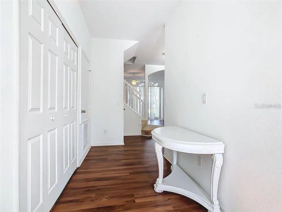A hallway with wood-look flooring leads toward a staircase and an open living area — 4715 HEMINGWAY HOUSE STREET, KISSIMMEE, FL