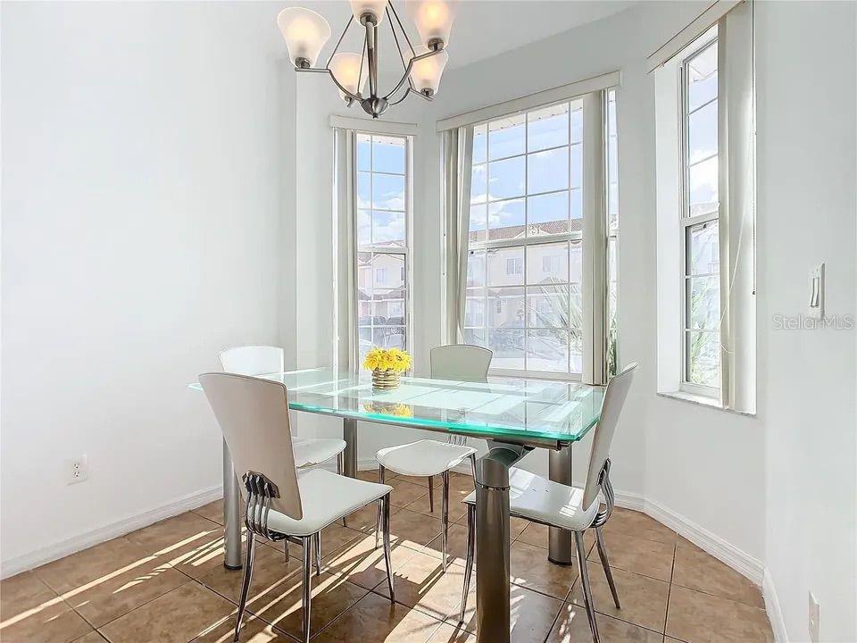 A dining area features a glass-topped table, four white chairs, and a chandelier — 4715 HEMINGWAY HOUSE STREET, KISSIMMEE, FL