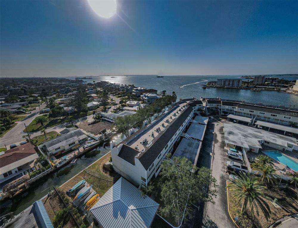 An aerial view shows a multi-story residential building near a canal and the ocean — 433 S PAULA DRIVE UNIT 17, DUNEDIN, FL