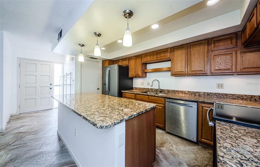 A kitchen features granite countertops, wood cabinets, stainless steel appliances, and a large center island — 433 S PAULA DRIVE UNIT 17, DUNEDIN, FL