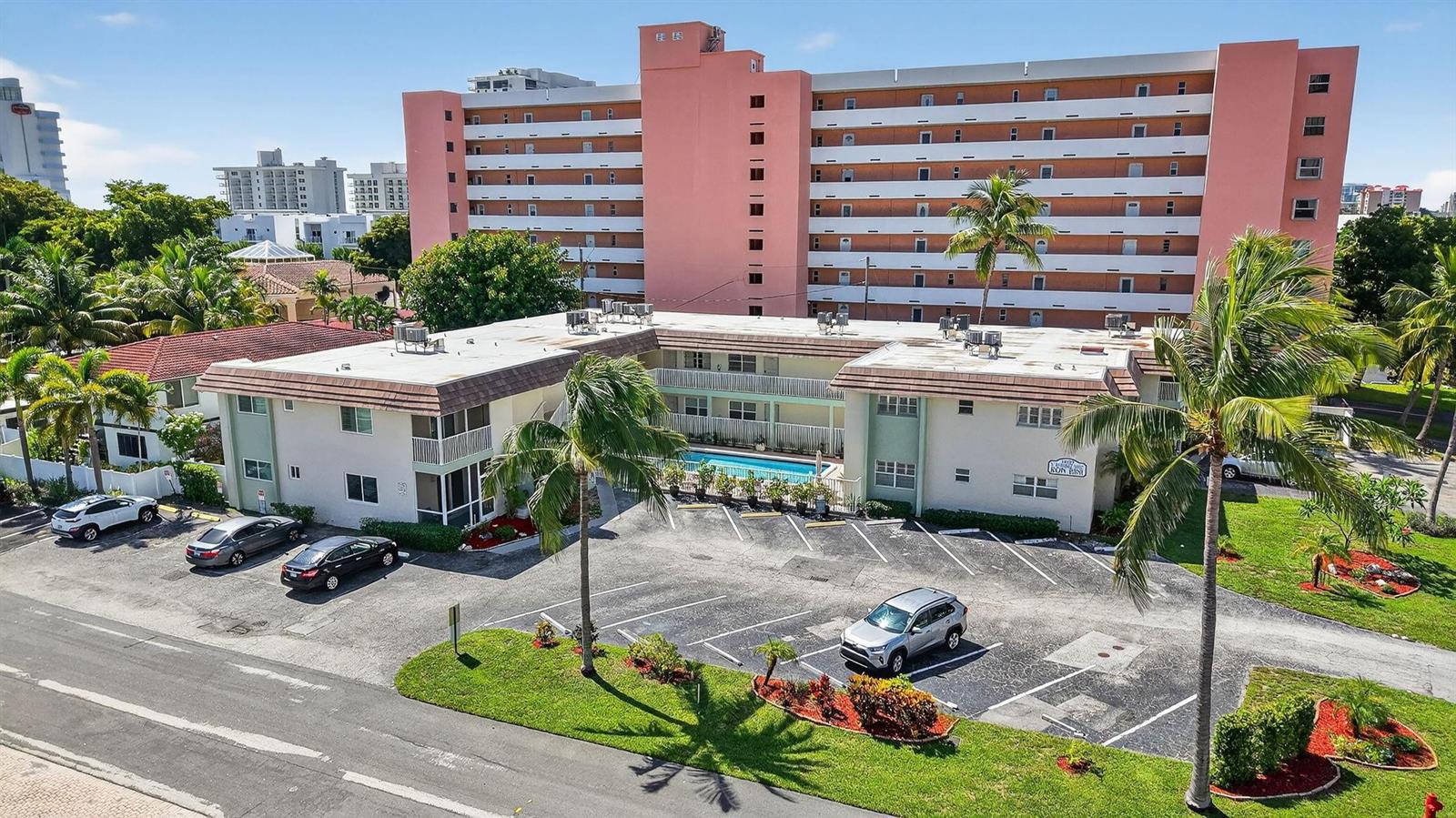 An aerial view shows a two-story apartment building with a pool and parking lot — 1450 N Riverside Drive # 102, Pompano Beach FL 33062, POMPANO BEACH, FL