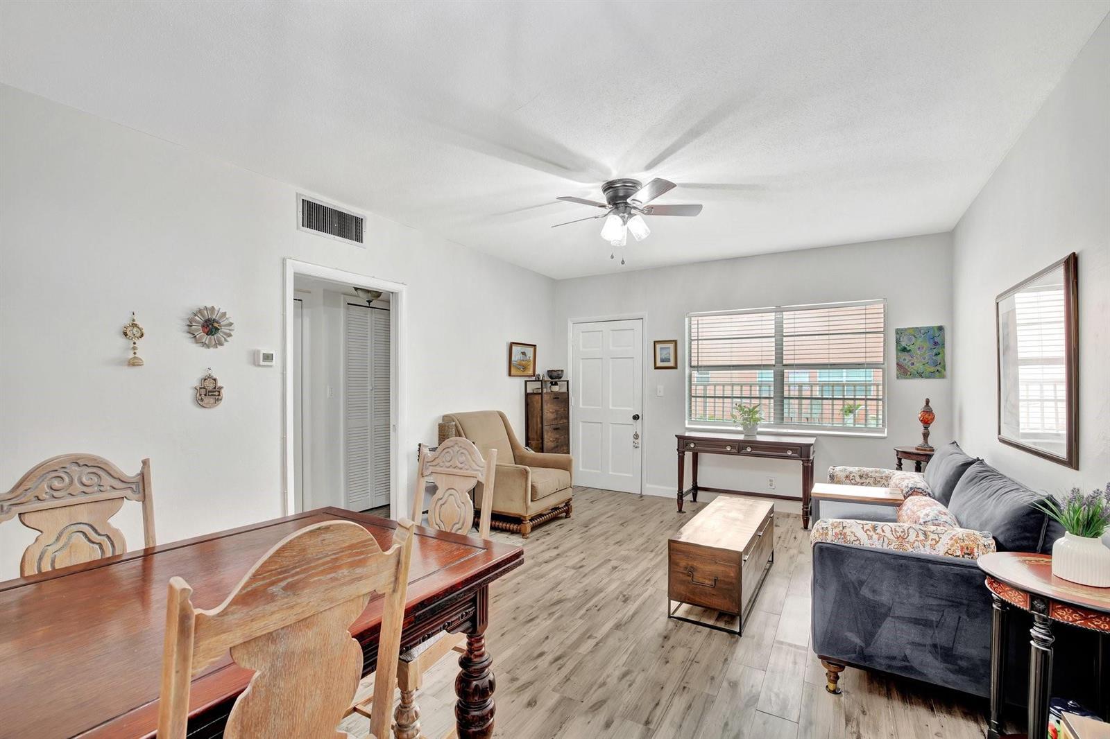 A living and dining area with wood-look flooring, a ceiling fan, and a dark sofa — 1450 N Riverside Drive # 102, Pompano Beach FL 33062, POMPANO BEACH, FL
