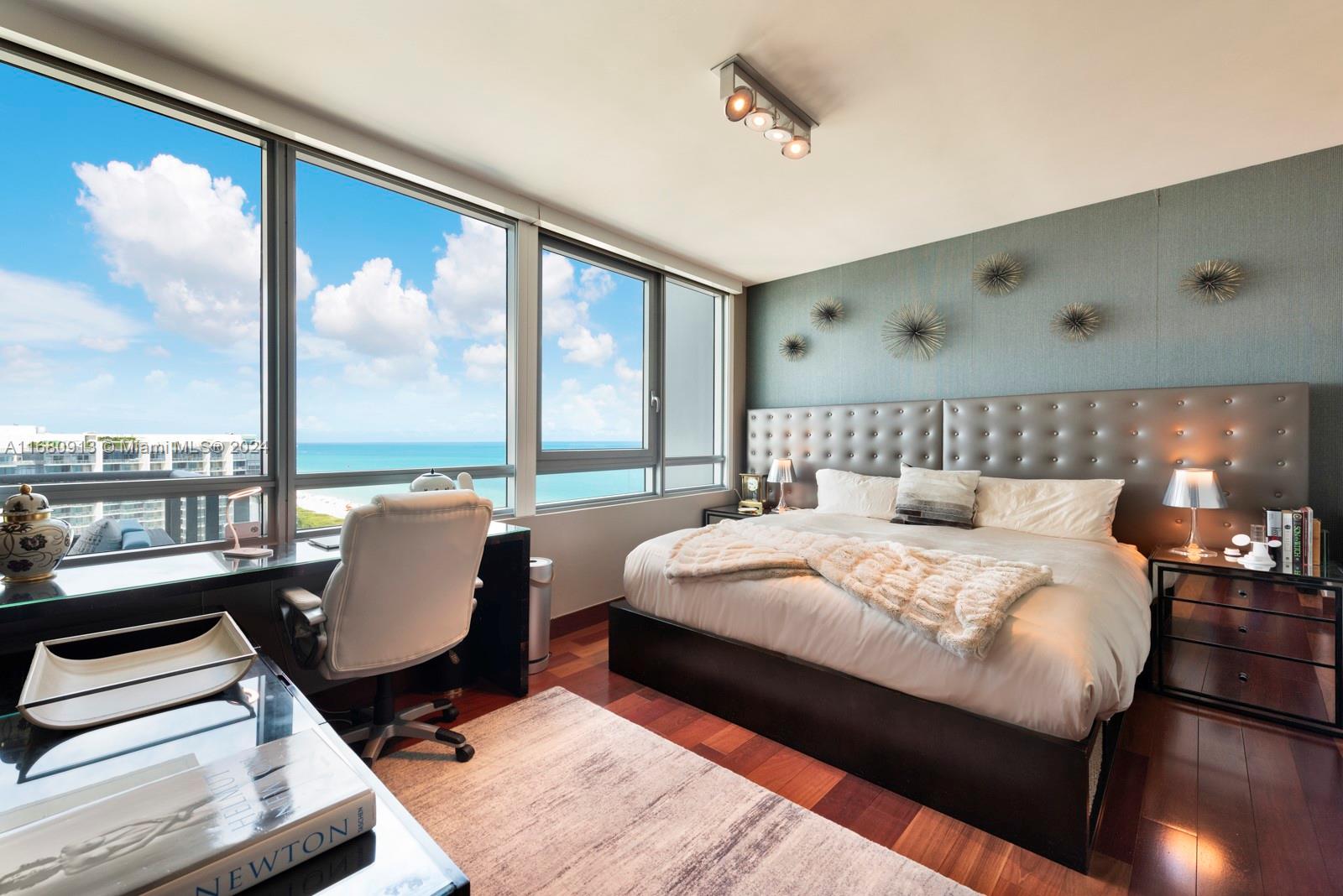A bedroom features a large bed, a desk by floor-to-ceiling windows, and ocean views — 101 20TH ST # 2603, Miami Beach FL 33139, MIAMI BEACH, FL