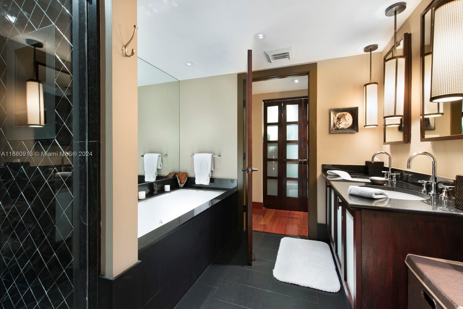 A bathroom features a soaking tub, double vanity with dark cabinetry, and a glass shower — 101 20TH ST # 2603, Miami Beach FL 33139, MIAMI BEACH, FL