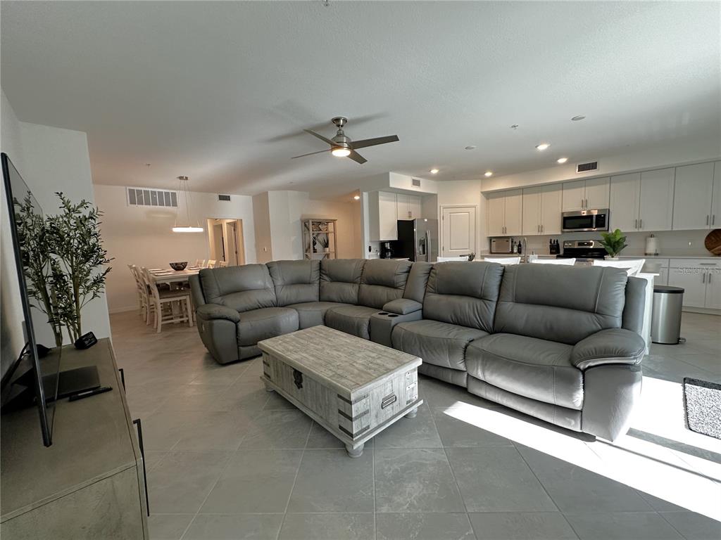 A living room with a large gray sectional sofa, a wooden coffee table, and an open kitchen — 14161 POPPY FIELD LOOP UNIT 5811, PUNTA GORDA, FL
