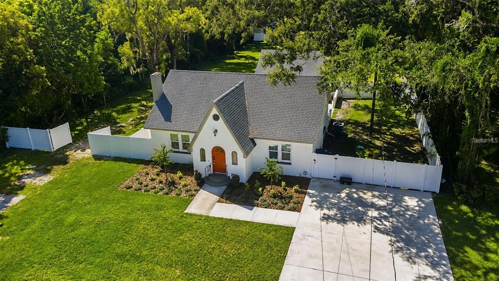 An aerial view shows a white cottage-style house with a steep roof and orange door — 3104 W LAMBRIGHT STREET, TAMPA, FL