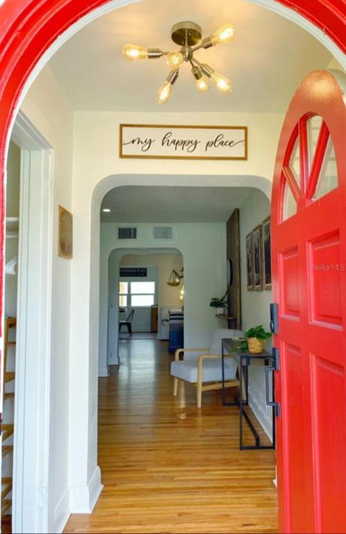 A bright entryway features a red door, hardwood floors, and a modern gold light fixture — 3104 W LAMBRIGHT STREET, TAMPA, FL