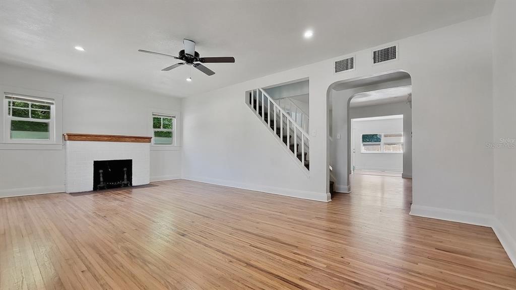 A living room with hardwood floors, a white brick fireplace, and a staircase — 3104 W LAMBRIGHT STREET, TAMPA, FL