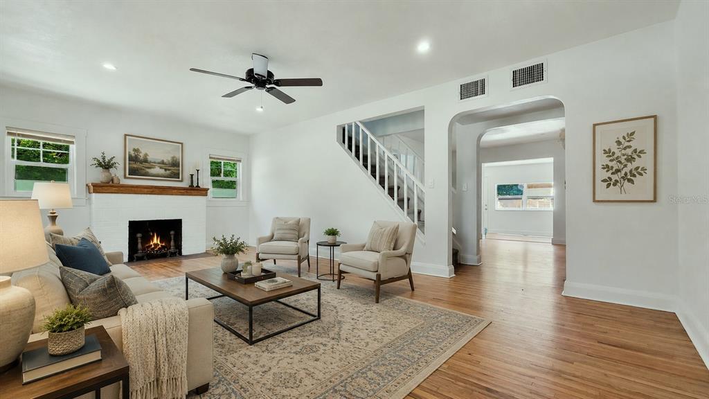 A living room features a fireplace, hardwood floors, a staircase, and neutral furniture — 3104 W LAMBRIGHT STREET, TAMPA, FL