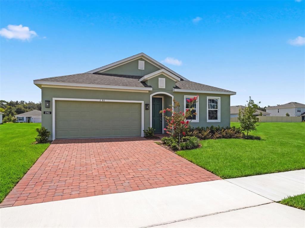 A single-story green house with a brick driveway and a two-car garage — 1981 EDUCATION STREET, ST CLOUD, FL