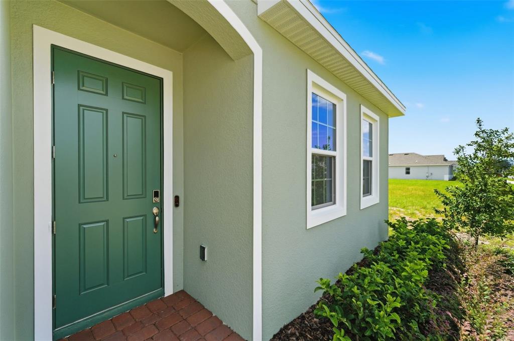 The exterior of a house features a green front door and light green stucco siding — 1981 EDUCATION STREET, ST CLOUD, FL