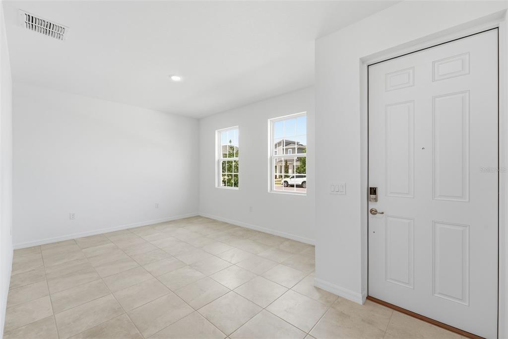 An empty room with white walls, tiled flooring, two windows, and a white front door — 1981 EDUCATION STREET, ST CLOUD, FL