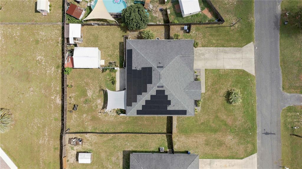 An aerial view shows a house with solar panels on its roof and a backyard — 10544 SE 54TH AVENUE, BELLEVIEW, FL