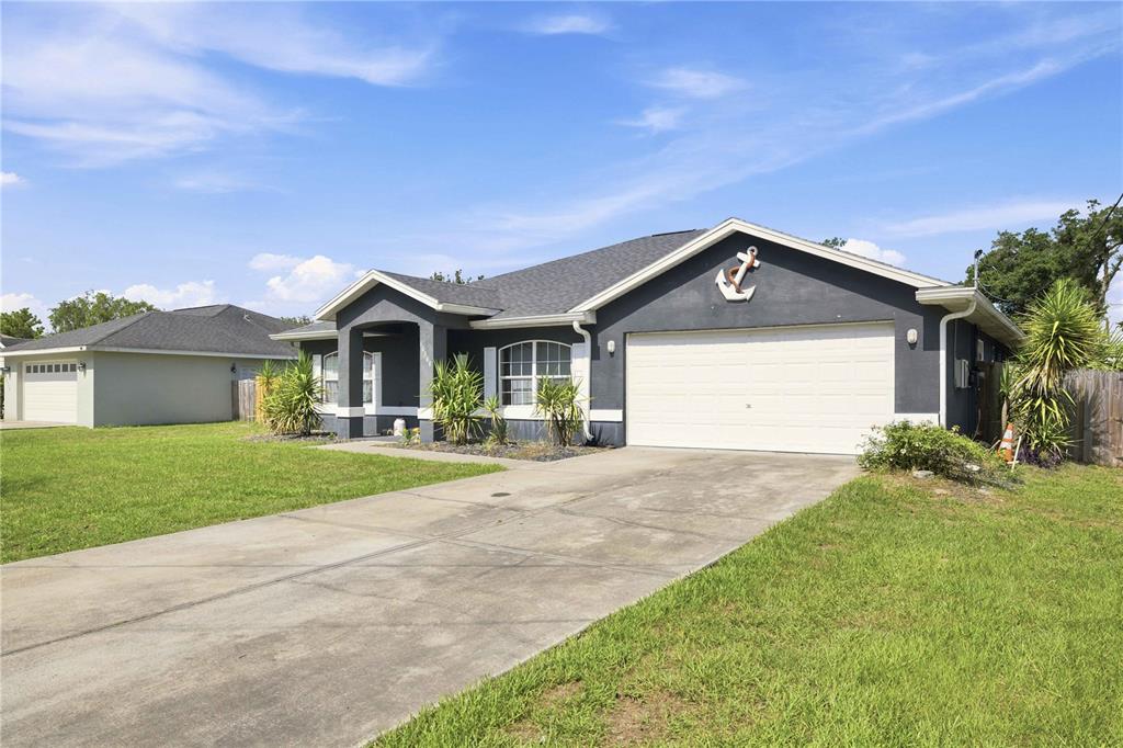 A single-story house with a dark gray exterior, white garage door, and a decorative anchor — 10544 SE 54TH AVENUE, BELLEVIEW, FL