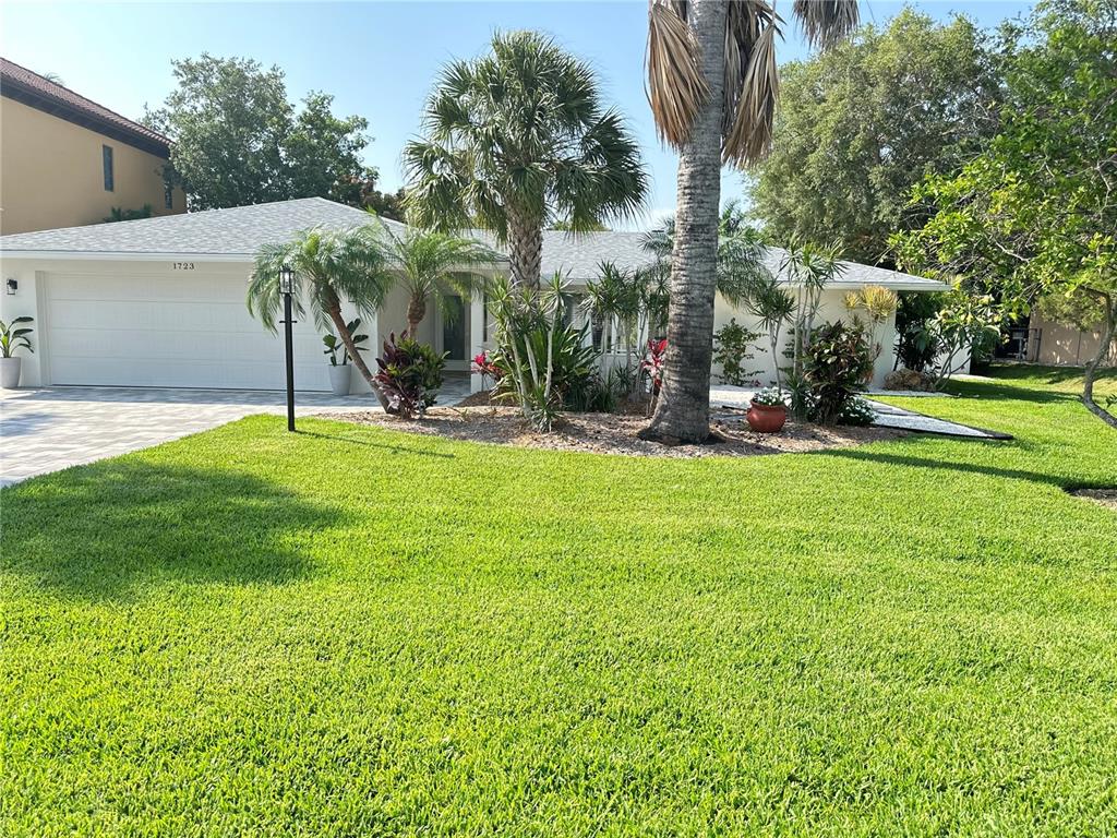 A single-story house with a white garage, palm trees, and a manicured lawn — 1723 STANFORD LANE, SARASOTA, FL
