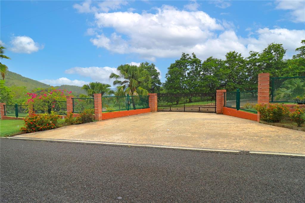 A paved driveway leads to a gated entrance with brick pillars and surrounding lush landscaping — 150 CARR UNIT 10.8km, VILLALBA, PR