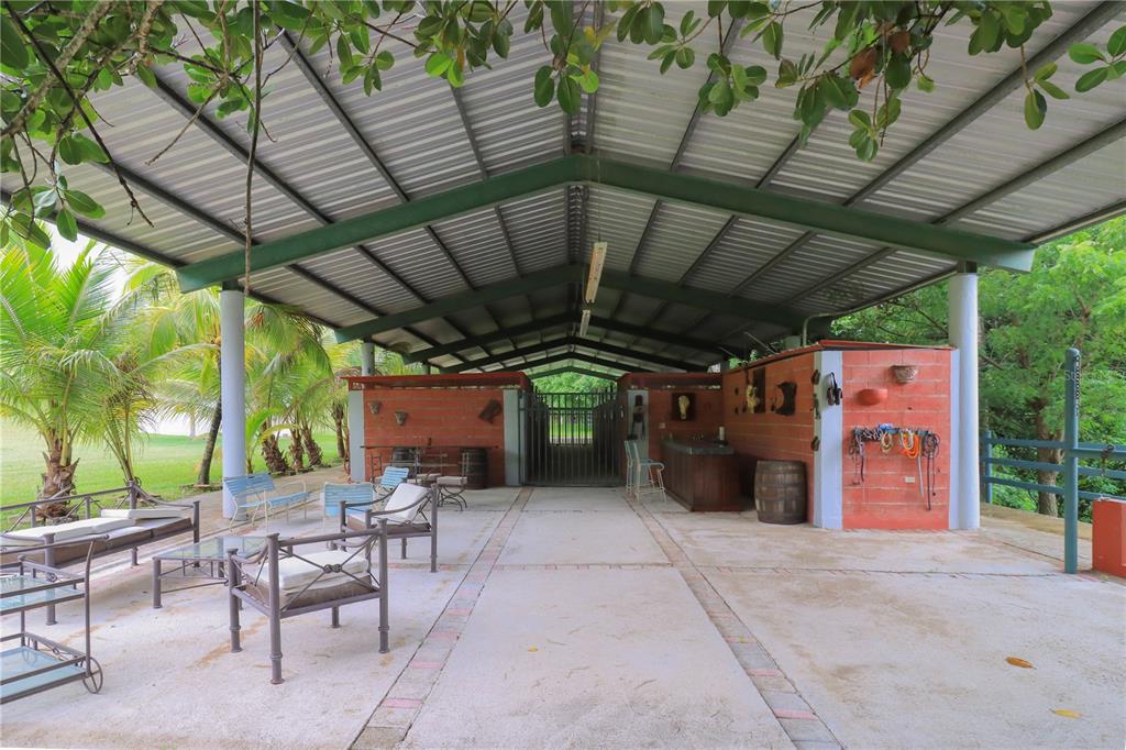 An open-air covered patio features a concrete floor, brick walls, and outdoor seating furniture — 150 CARR UNIT 10.8km, VILLALBA, PR