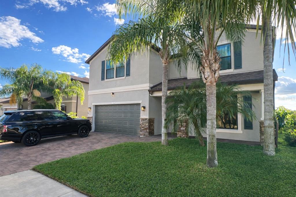 A covered entryway features a blue front door, a brick porch, and a flowering bush — 1907 BOTTLEBRUSH WAY, NORTH PORT, FL
