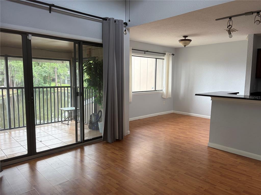 A living room with wood-look flooring, a sliding glass door, and a view of water — 5926 PEREGRINE AVENUE UNIT A13, ORLANDO, FL
