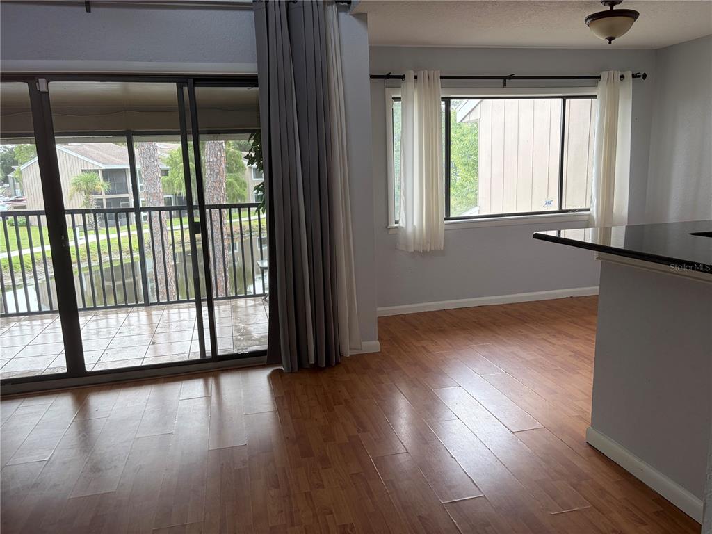 This room features wood-look flooring, a sliding glass door to a balcony, and a window — 5926 PEREGRINE AVENUE UNIT A13, ORLANDO, FL