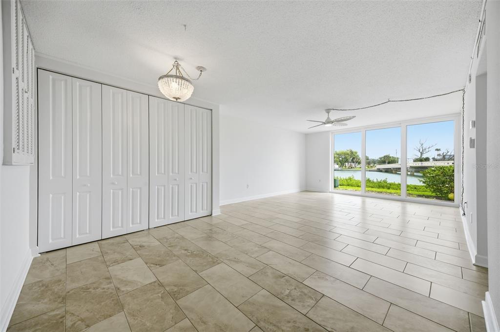 A bright, tiled room features white bi-fold closet doors, a ceiling fan, and large windows — 7465 BAY ISLAND DRIVE S UNIT 112, SOUTH PASADENA, FL