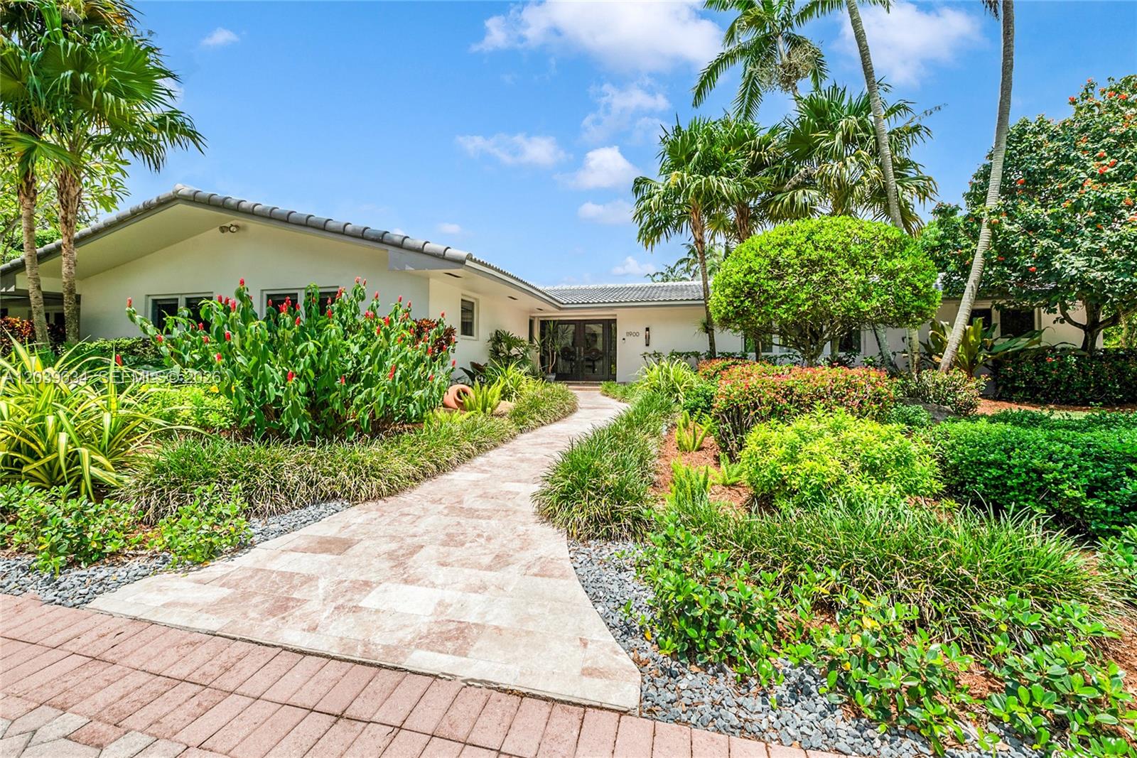 A stone walkway leads to the entrance of a single-story house surrounded by lush landscaping — 11900 SW 63rd Ave, Pinecrest FL 33156, PINECREST, FL