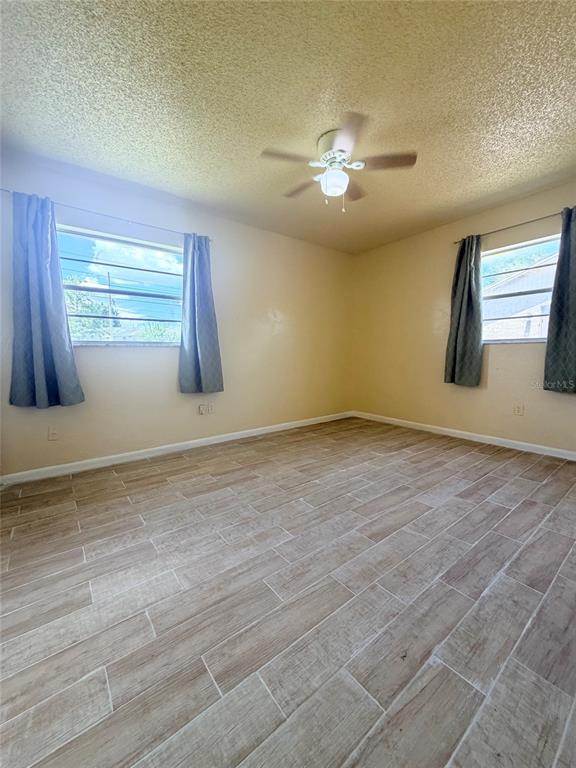 An empty bedroom features light-colored wood-look tile flooring, yellow walls, and a ceiling fan — 5425 KAREN COURT, ORLANDO, FL