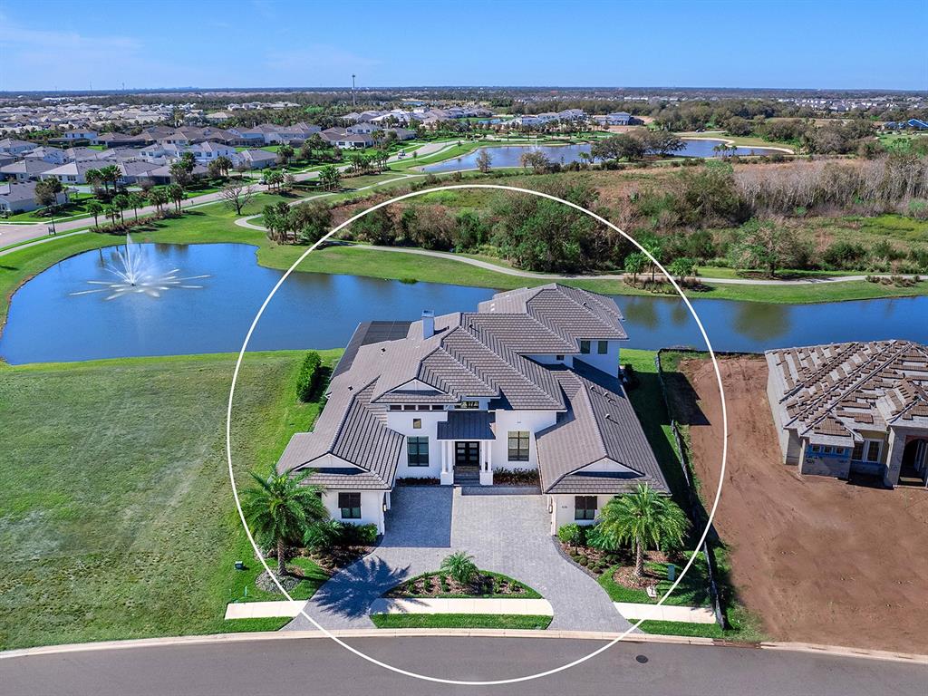An aerial view shows a modern house with a tiled roof and a circular driveway — 4218 BUTTE TRAIL, LAKEWOOD RANCH, FL